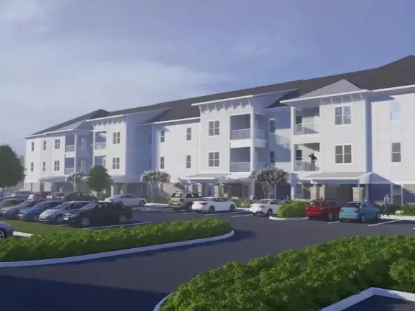The exterior of The Gardens, a modern apartment complex with parking lot in Lakeland, FL.